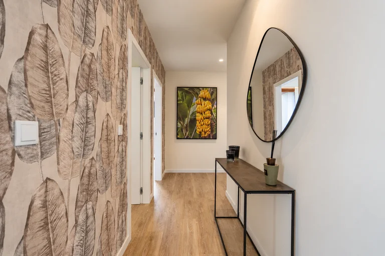Hall com espelho oval e papel de parede com folhas