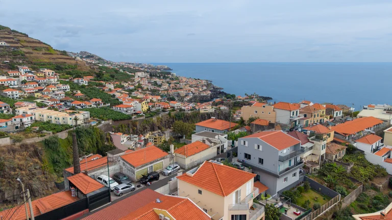 Panorâmica da costa, com os telhados em primeiro plano e o mar ao fundo